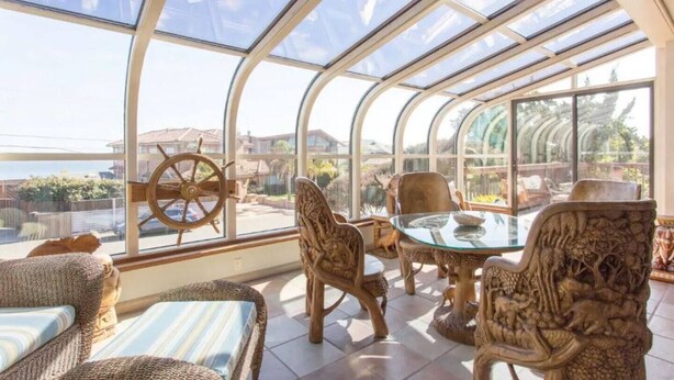 A sunroom with a glass ceiling, wicker furniture, and a view of the outside. - Opal Cliff Beach House (Pleasure Point)