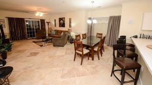 A spacious living room with a large dining table, comfortable seating, and a kitchen area with bar stools. - Beautiful private end unit! Featuring 2b/2b near swimming pool.   (Myrtle Beach)