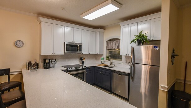 A kitchen with white cabinets, stainless steel appliances, and a central island with seating. - Beautiful private end unit! Featuring 2b/2b near swimming pool.   (Myrtle Beach)
