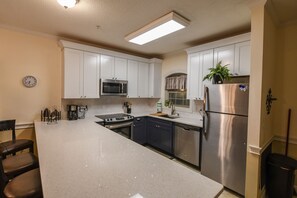 A kitchen with white cabinets, stainless steel appliances, and a central island with seating.