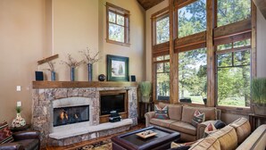 A cozy living room with a stone fireplace, large windows, and comfortable seating. - Dog-Friendly Villa, Steps Away From Old Greenwood's Driving Range! (Truckee)