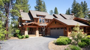 A large log cabin with a spacious driveway, multiple garage doors, and a well-maintained front yard with trees and shrubs. - Dog-Friendly Villa, Steps Away From Old Greenwood's Driving Range! (Truckee)
