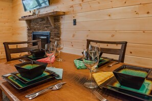 A wooden dining table set with black bowls and wine glasses, with a stone fireplace in the background. - Beautiful Private Cabin, adjacent to the National Forest (Luray)