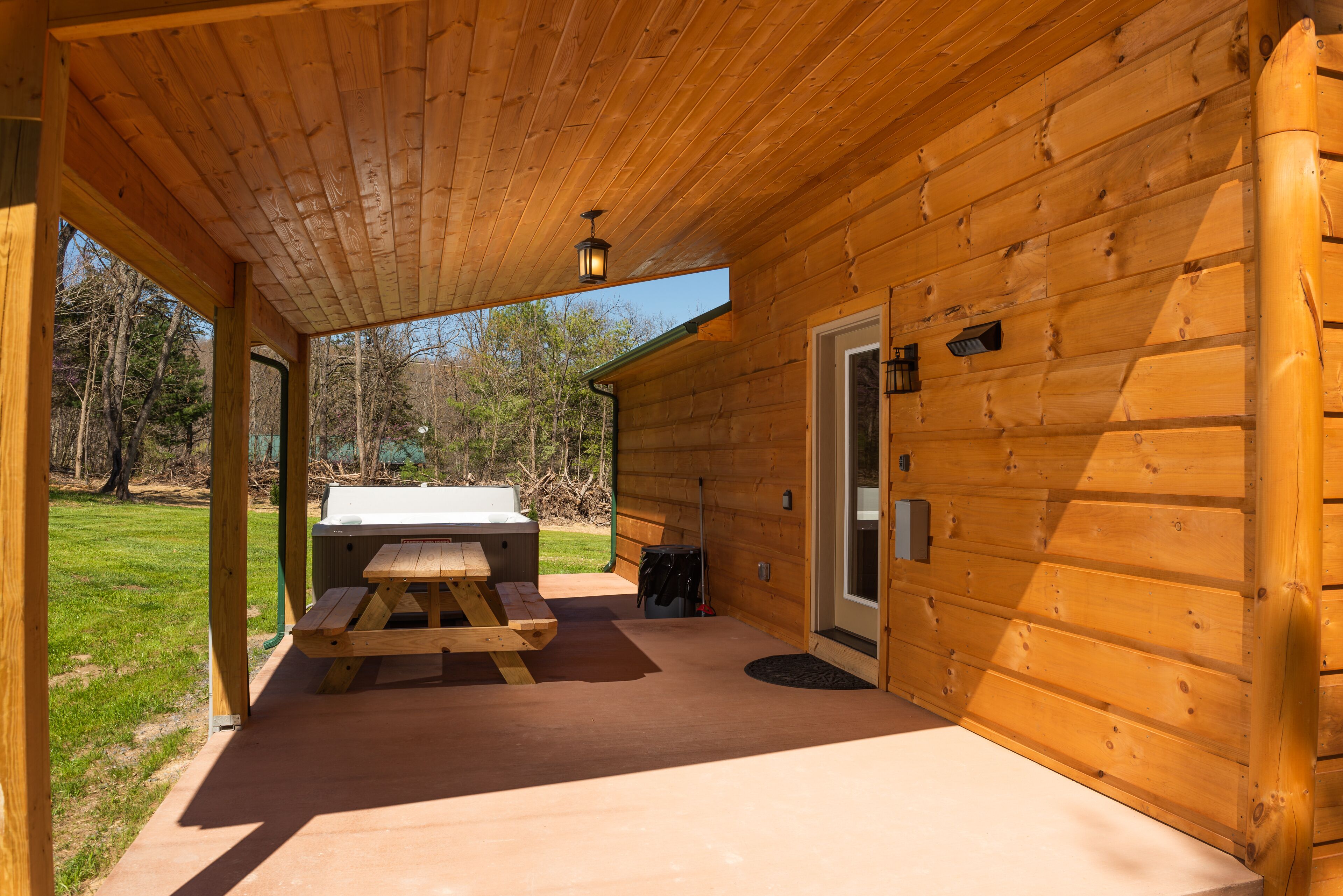 Una baita in legno con un portico coperto, un tavolo da picnic e un barbecue.