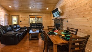 A wooden cabin interior with a living room, dining area, leather sofa, and a fireplace. - Beautiful Private Cabin, adjacent to the National Forest (Luray)