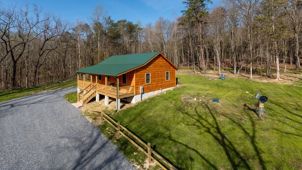 A wooden cabin with a green roof, a porch, and a gravel driveway. - Beautiful Private Cabin, adjacent to the National Forest (Luray)