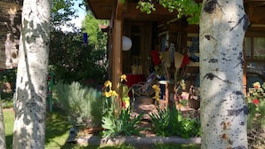A wooden house with a porch, surrounded by greenery and a garden path.