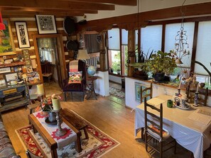Une pièce chaleureuse et bien éclairée, avec un plancher en bois, une table à manger entourée de chaises, un fauteuil confortable, un globe terrestre et divers objets décoratifs.