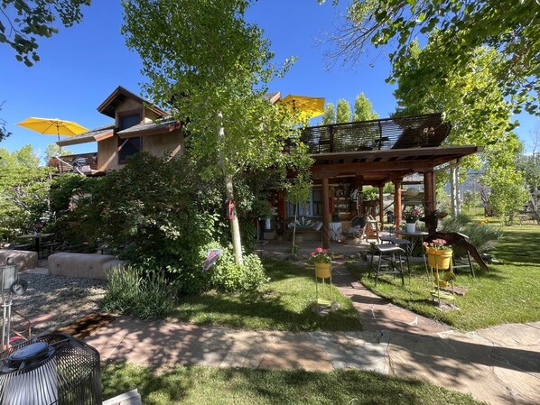Un espace patio aménagé avec du mobilier d’extérieur, une pergola et un coin salon abrité.