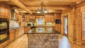 A spacious kitchen with wooden cabinets, a stone island, and a large window. - Lakefront Home Full size Bar Games Fire Pit (Ellijay)