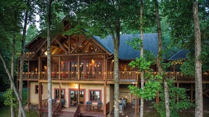 A two-story log cabin with a balcony, surrounded by trees. - Lakefront Home Full size Bar Games Fire Pit (Ellijay)