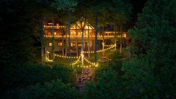 A lodge with multiple levels, outdoor seating, and string lights in a forested area. - Lakefront Home Full size Bar Games Fire Pit (Ellijay)