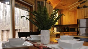 A dining table with white bowls and a white vase with green foliage.