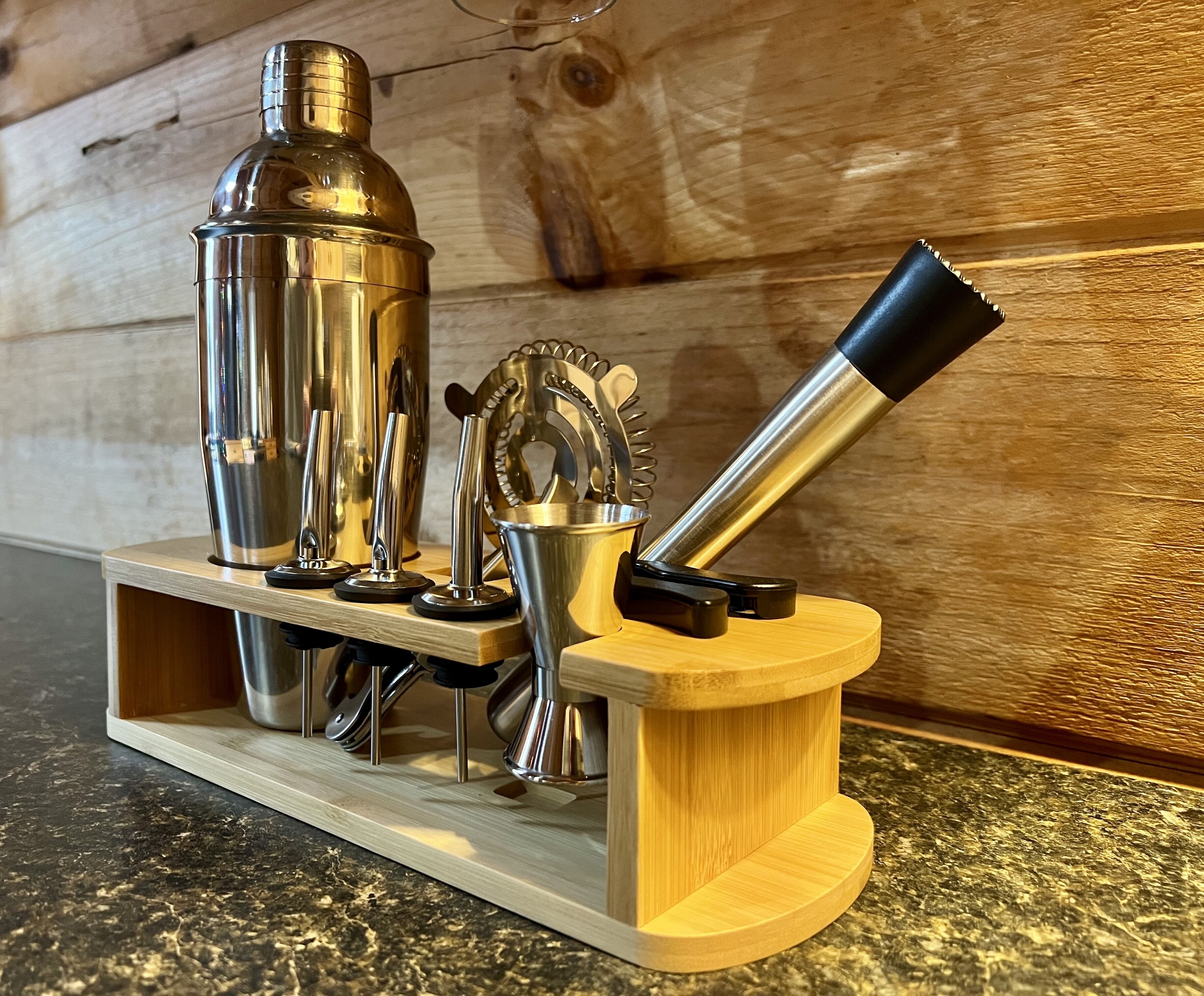 Ein Set aus Bartools aus Holz mit Shaker, Stößel und Sieb aus Metall auf einer Holzablage.