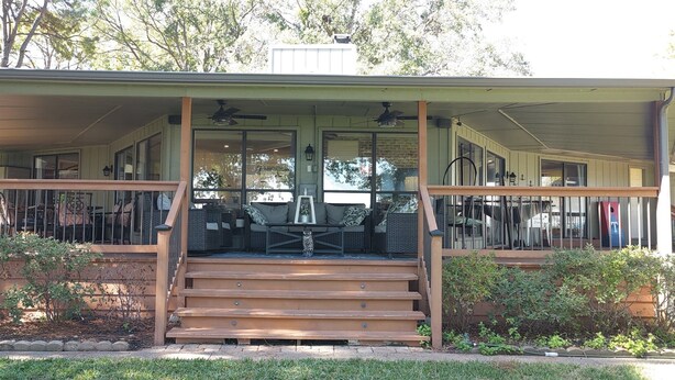 A covered porch with outdoor seating, a staircase leading to the entrance, and a view of the street.