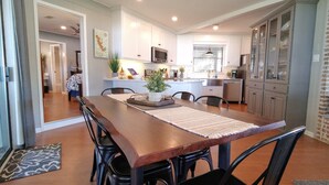 A spacious kitchen with white cabinets, a central island, and a dining area with a wooden table and chairs.