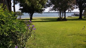 A well-maintained grassy area with trees and a body of water in the background.