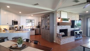A modern kitchen with white cabinets, a central island, and a brick fireplace.