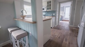 A kitchen with a wooden countertop, a sink, and two bar stools.