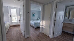 A hallway leading to a bedroom with a bed, a bathroom with a mirror, and a door.