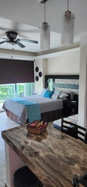 Une chambre à coucher avec un lit, des tables de chevet, un ventilateur de plafond et une fenêtre donnant sur un beau paysage.