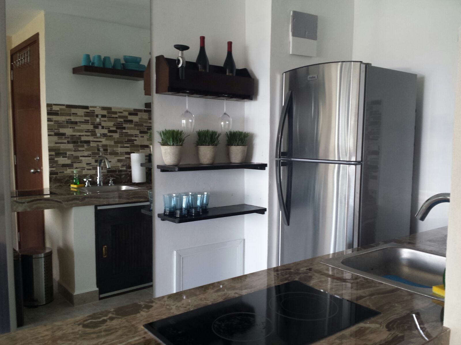 A modern kitchen with a stainless steel refrigerator, a built-in oven, and a black countertop.