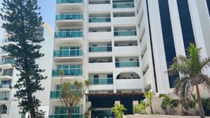 A multi-story hotel with a modern design, featuring balconies and a prominent entrance with steps.