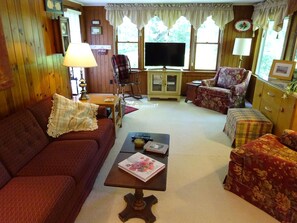 Relax in this inviting living room with a comfortable sofa, matching ottoman, and plaid armchair.