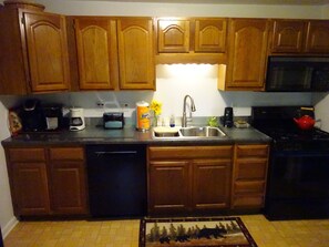 Compact kitchen area with a sink, coffee maker, toaster, and coffee can.