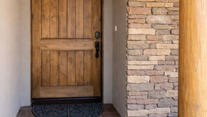 A wooden door with a stone wall and a doormat. - Unbelievable Views, Perfect Location, Ski, Golf, Mountain Home (Ruidoso)
