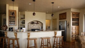 A kitchen with a central island, bar stools, wooden cabinets, and pendant lighting. - Unbelievable Views, Perfect Location, Ski, Golf, Mountain Home (Ruidoso)