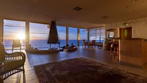 Ein geräumiges Wohnzimmer mit großem Fenster zum Meer, einem Kamin und einer Bar.