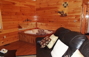 Relax in a cozy cabin with a leather sofa, wooden bench, and a large bathtub.