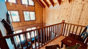 Una cabaña de madera con balcón, ventanas amplias y vistas al exterior.