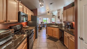 A kitchen with wooden cabinets, a stove, a microwave, and a refrigerator. - Pool and Spa (Private) - Tucson Arizona Home (Tucson)