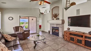 A living room with a leather sofa, a glass coffee table, a fireplace, a TV, and a ceiling fan. - Pool and Spa (Private) - Tucson Arizona Home (Tucson)