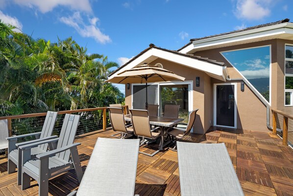 A deck with outdoor furniture, a table, and an umbrella. - 5 Bedroom Open Plan with Ocean Views, Queens Bath, Bali Hai, and Golf Course (Princeville)