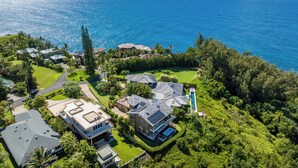 Oversigtsbillede af et kystnært boligområde med huse, en swimmingpool og udsigt til havet.