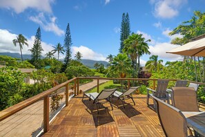 A wooden deck with lounge chairs and a table, overlooking a lush garden and a body of water. - 5 Bedroom Open Plan with Ocean Views, Queens Bath, Bali Hai, and Golf Course (Princeville)