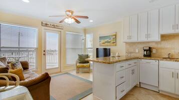 A modern kitchen with white cabinets, a granite countertop, and a built-in dishwasher.