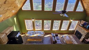 Una habitación con una mesa de comedor para seis personas, un sofá, una chimenea y ventanas amplias que ofrecen vistas al exterior.