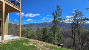 Una terraza de madera con vistas a montañas y árboles.