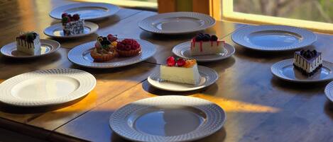 A table with various desserts on plates, arranged on a wooden table with a view outside.