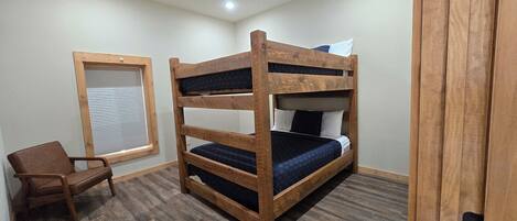 A bunk bed with a wooden frame, a chair, and a window with blinds.