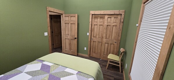 Ein Schlafzimmer mit einem Bett, einem Sessel und zwei Holztüren.