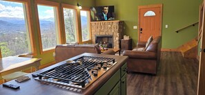 Una sala de estar con chimenea, televisor y vistas a la montaña.