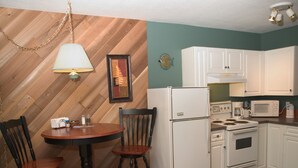 A compact kitchen with a refrigerator, stove, microwave, and a dining area with a table and chairs.