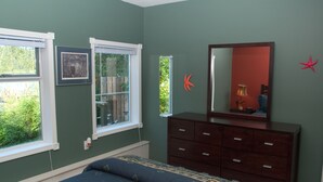 A bedroom with a bed, dresser, and two windows.