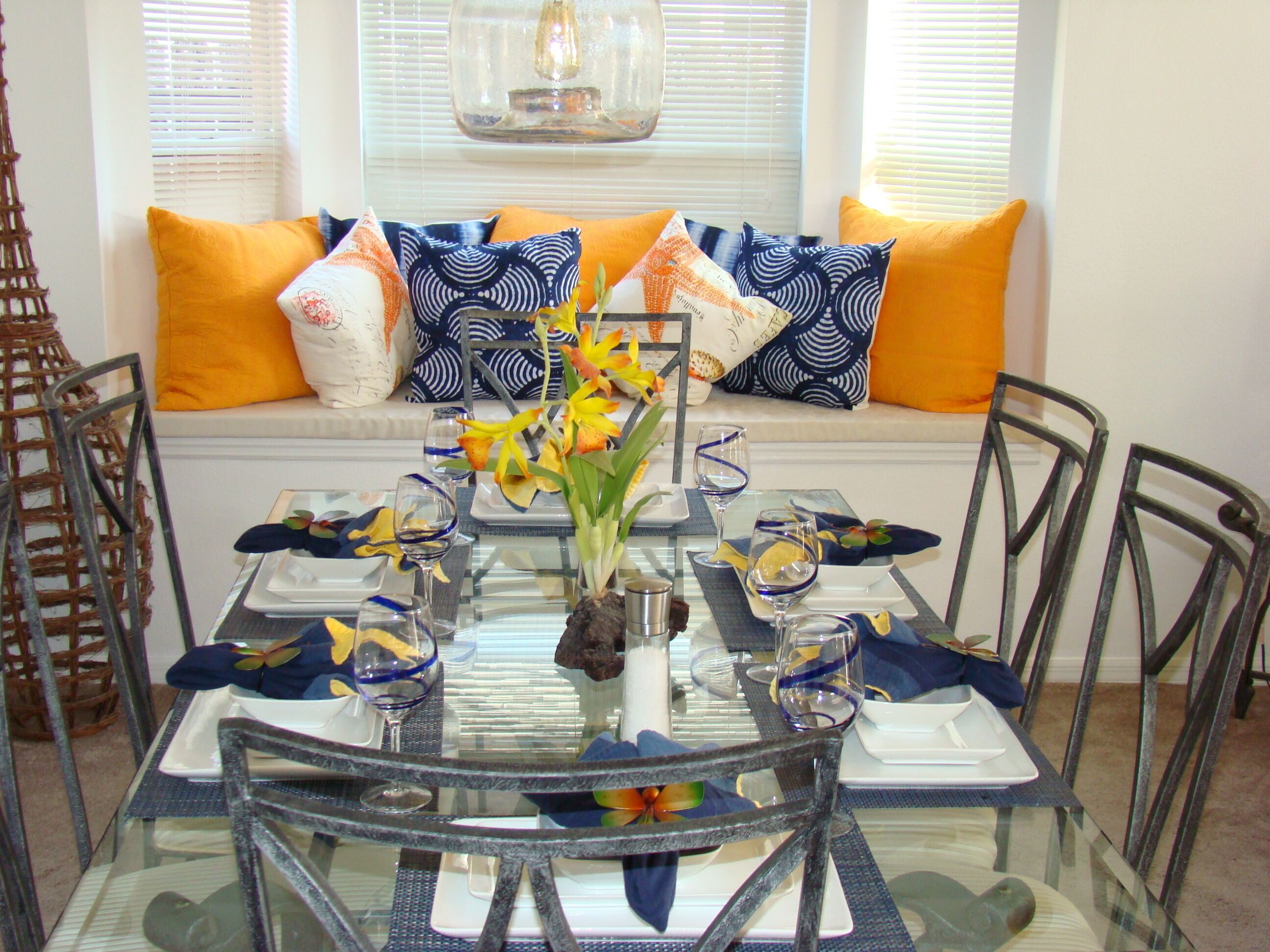 A dining table set for six with a glass top, surrounded by chairs.