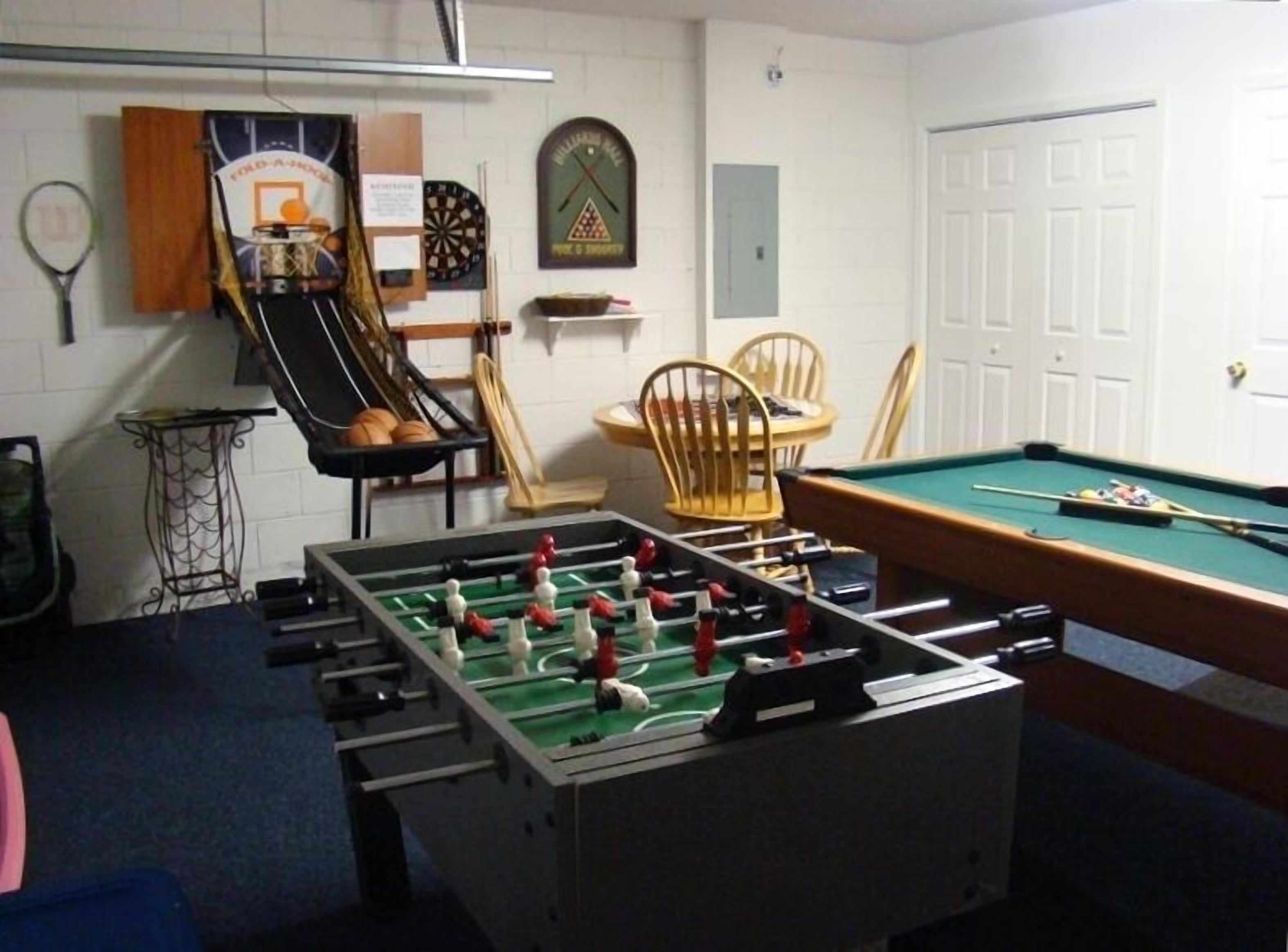 A room with a foosball table, a pool table, and various sports memorabilia on the walls.